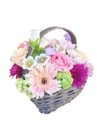 Compozione di fiori sulle tonalità del rosa realizzata in cestino.